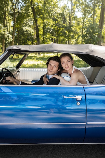 Free photo side view smiley married couple in blue car