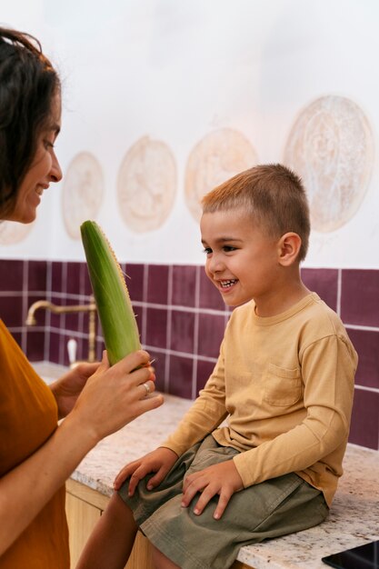 Free photo side view smiley mother and kid with corn