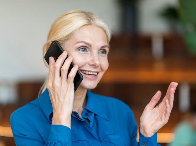 Foto gratuita vista laterale della donna anziana sorridente che parla al telefono mentre si lavora