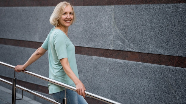 Vista laterale della donna senior di smiley che propone all'aperto