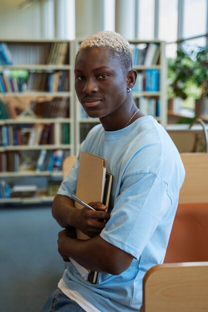 Free photo side view smiley student holding notebooks