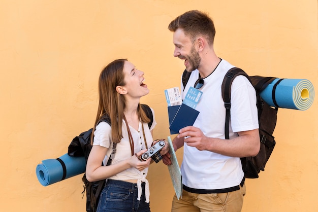 Free photo side view of smiley tourist couple with backpacks and passports