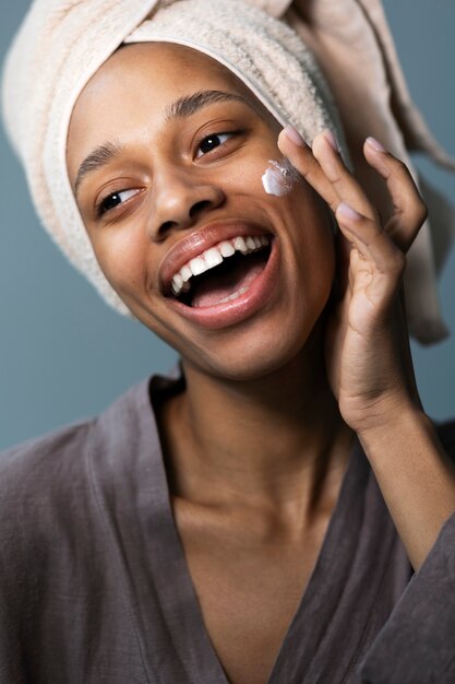 Side view smiley woman applying face cream