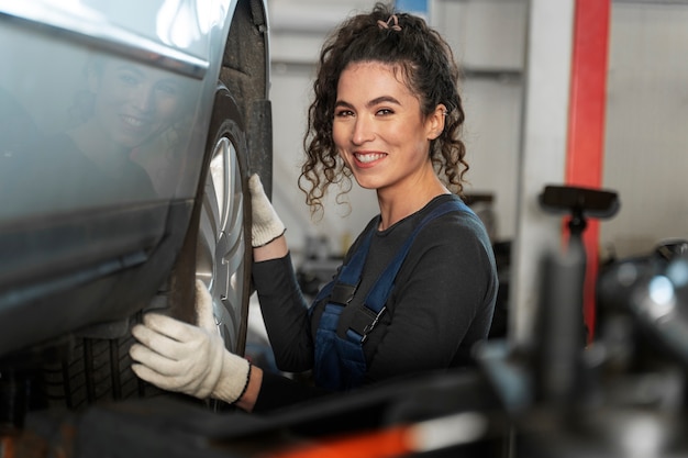 Free photo side view smiley woman changing wheel