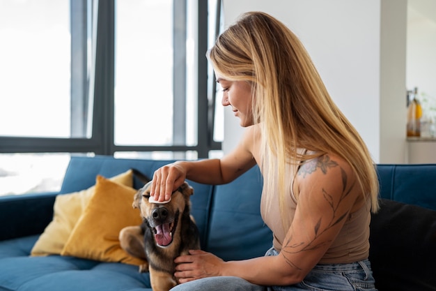 Free photo side view smiley woman cleaning dog