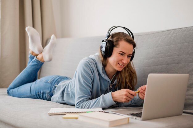 Side view of smiley woman on couch attending on online class