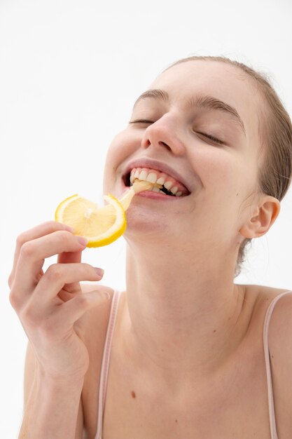 Side view smiley woman eating lemon