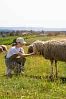 Foto gratuita donna sorridente di vista laterale che alimenta le pecore
