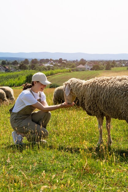 Side view smiley woman feeding sheep