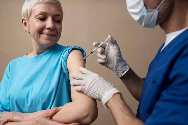 Foto gratuita donna sorridente di vista laterale che riceve il vaccino