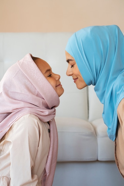 Free photo side view smiley woman and girl with hijabs