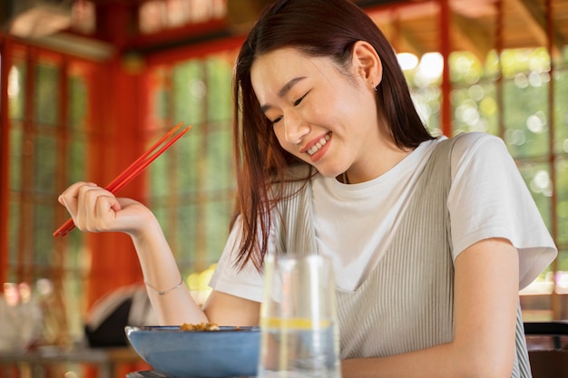 Free photo side view smiley woman holding chopsticks