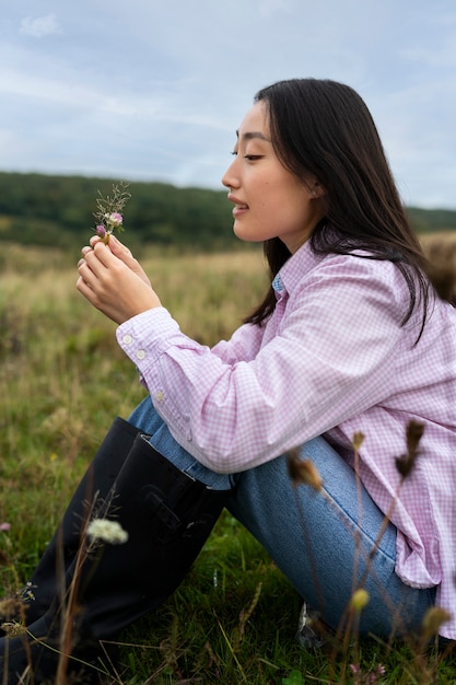 Foto gratuita fiore della holding della donna di smiley di vista laterale