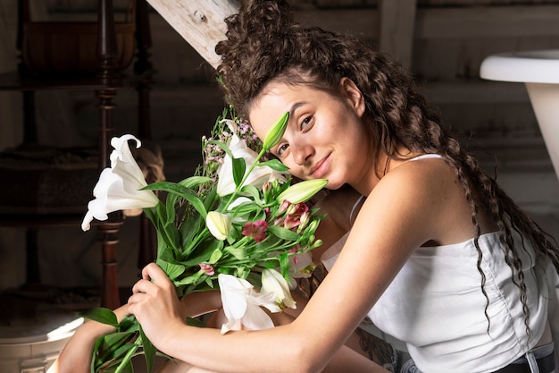 Foto gratuita fiori della holding della donna di smiley di vista laterale