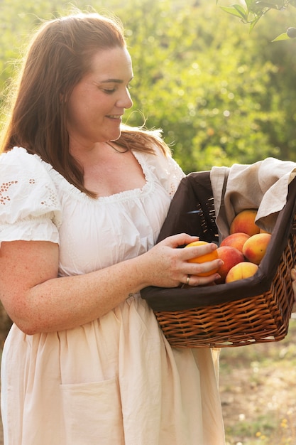 Free photo side view smiley woman holding fruit basket