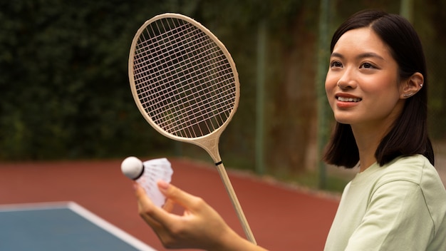 Side view smiley woman holding racket