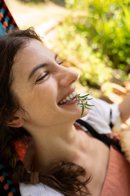 Free photo side view smiley woman laying in hammock