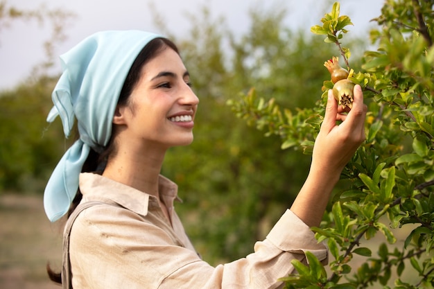 Free photo side view smiley woman looking at fruit