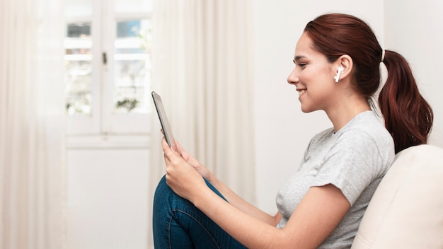 Free photo side view of smiley woman looking at tablet