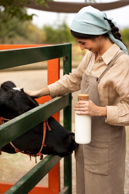 Foto gratuita donna sorridente di vista laterale che accarezza la mucca