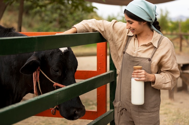 Donna sorridente di vista laterale che accarezza la mucca