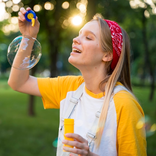 Side view of smiley woman playing with bubbles