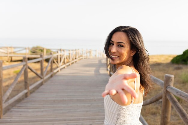 Side view of smiley woman posing outdoors with hand reaching