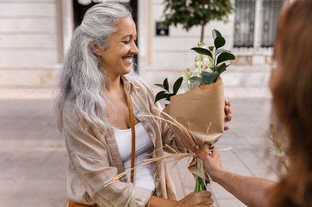 Donna sorridente di vista laterale che riceve i fiori