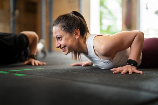 Donna sorridente di vista laterale che si allena in palestra