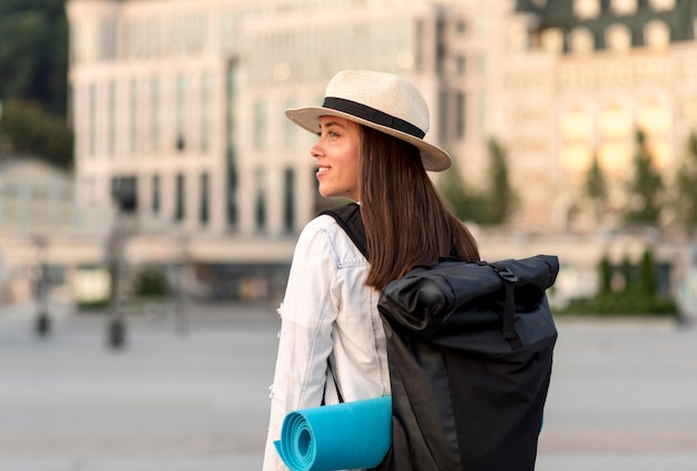 Улыбающаяся женщина, путешествующая одна с рюкзаком, вид сбоку