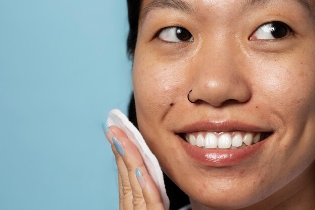 Side view smiley woman using cotton pad