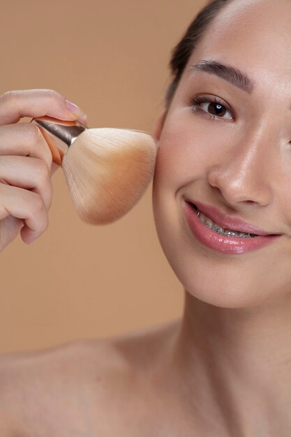 Side view smiley woman using makeup brush