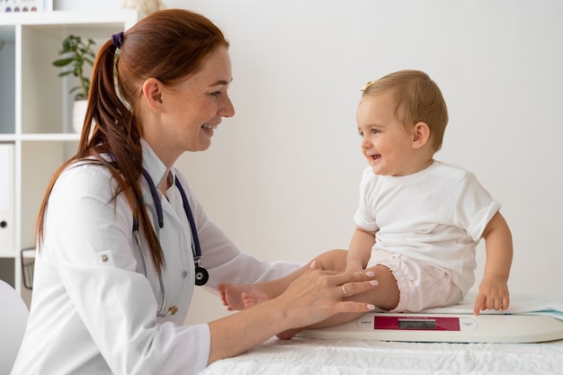 Free photo side view smiley woman weighing babies