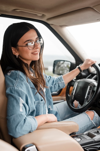 Side view of smiley woman with glasses traveling alone by car