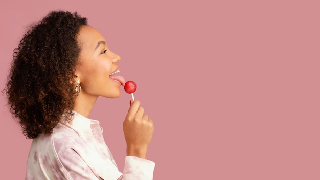 Free photo side view of smiley woman with lollipop and copy space