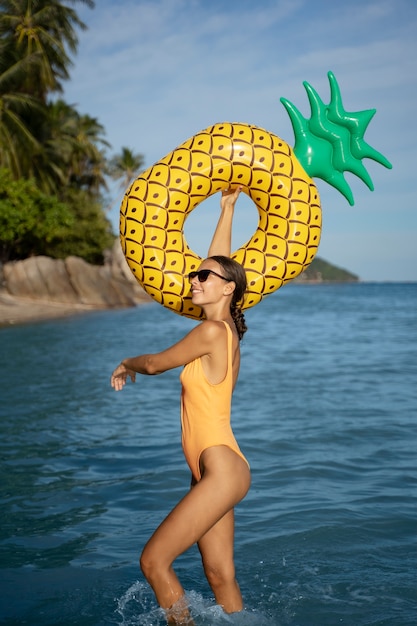 Free photo side view smiley woman with pineapple floater