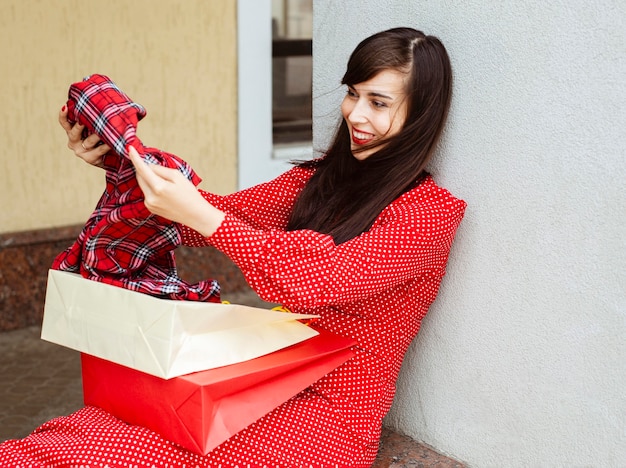 Side view of smiley woman with shopping bags and sale clothing