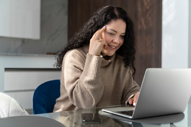 Вид сбоку улыбающаяся женщина, работающая на ноутбуке