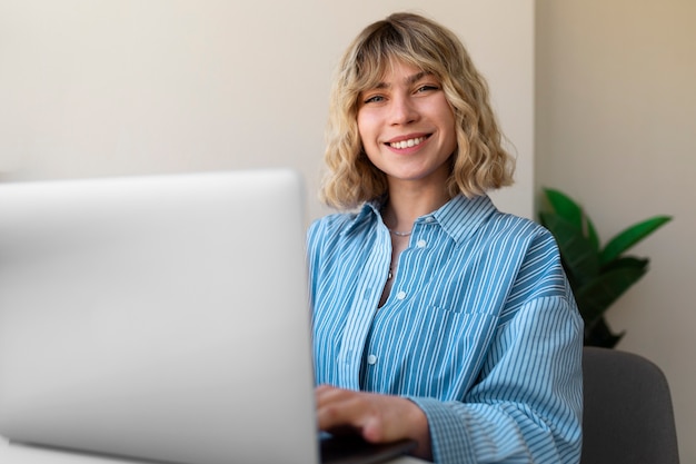 Free photo side view smiley woman working on laptop