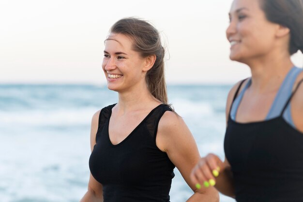 Side view of smiley women exercising on the beach
