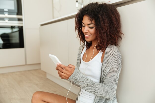 Side view of a smiling african woman sitting on the floor