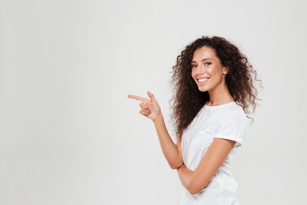 Side view of smiling curly woman pointing away