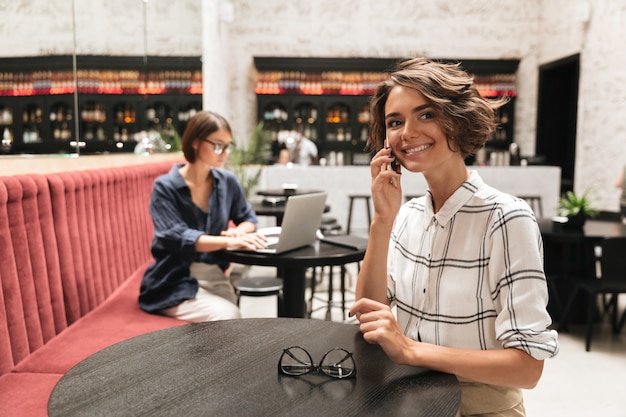 Free photo side view of smiling curly woman talking by the phone