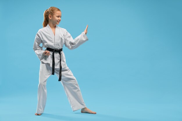 Вид сбоку улыбающаяся девушка в белом кимоно, обучение каратэ