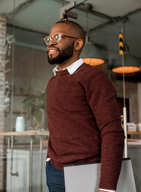 Side view of smiling man holding a laptop