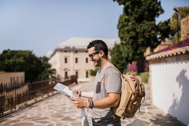 Side view of smiling man looking at map standing on street