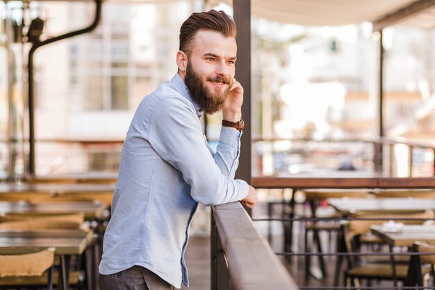 レストランで立っている笑顔の若い男の側面図