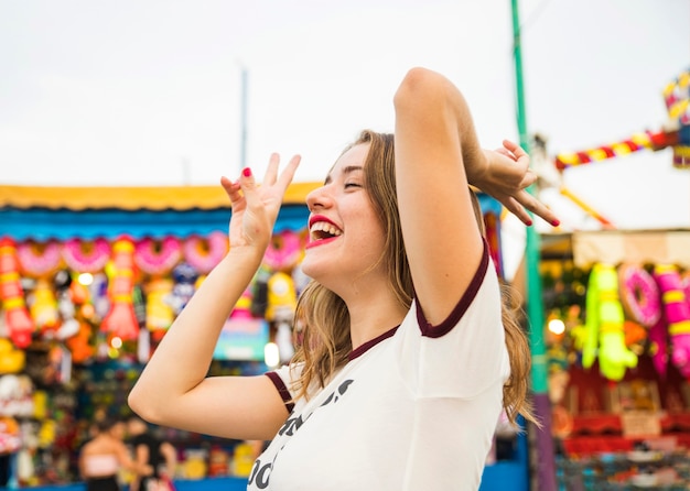 Side view of a smiling young woman gesturing peace sign