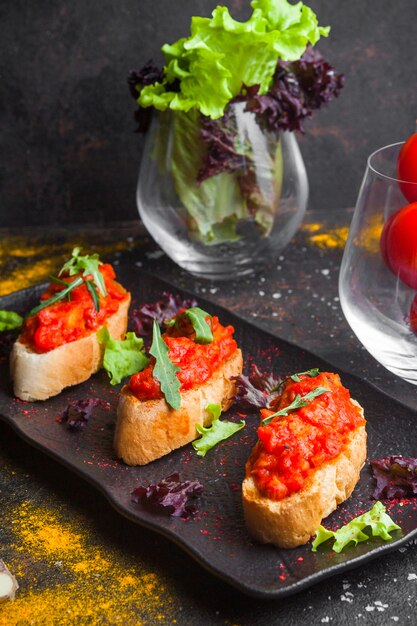 Side view snack with sliced bread from above tomato salad and arugula in dark plate