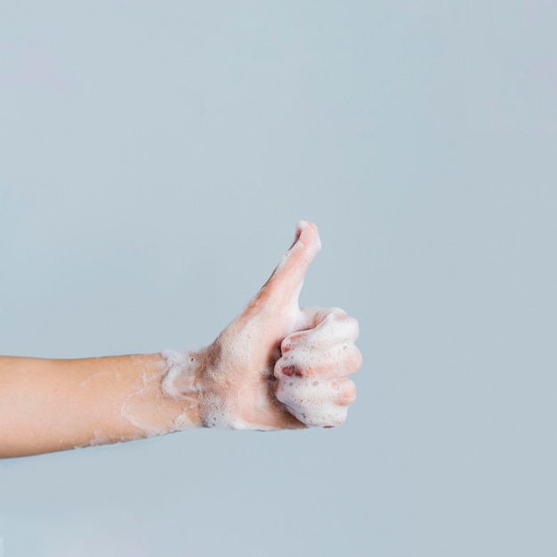 Side view of soapy hand giving thumbs up